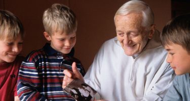 frère Roger met enkele kinderen, gebogen over een familiefoto